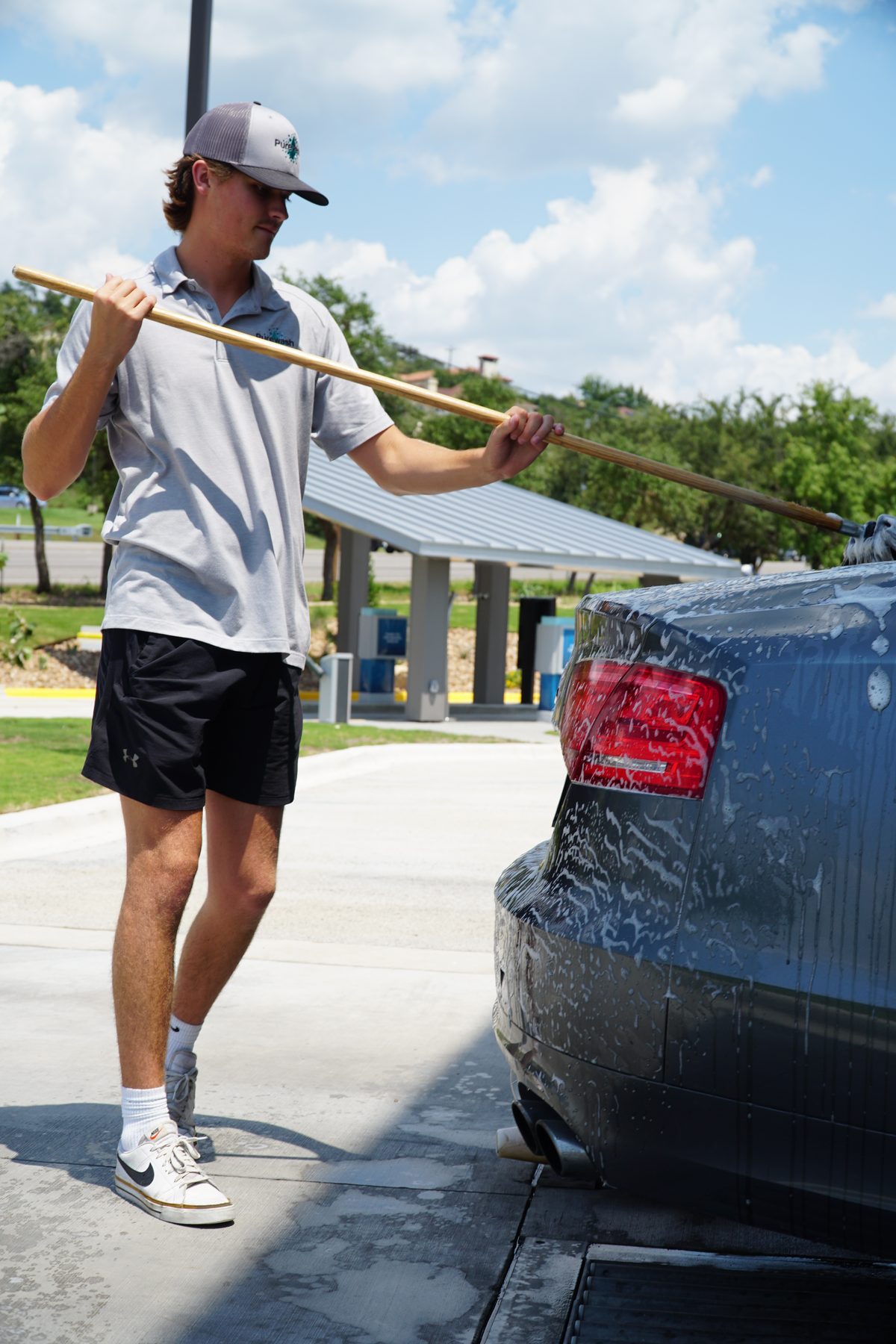 A Purewash crew member hand-brushing a sudsy car before the wash