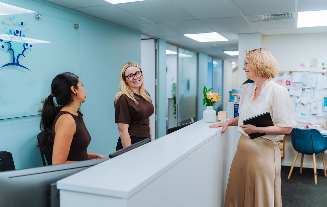 Three Totally Psyched colleagues talking at the clinic reception desk