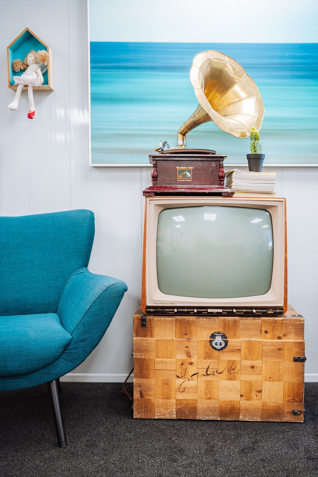 A corner of the Totally Psyched clinic with a teal armchair, vintage gramophone and retro television