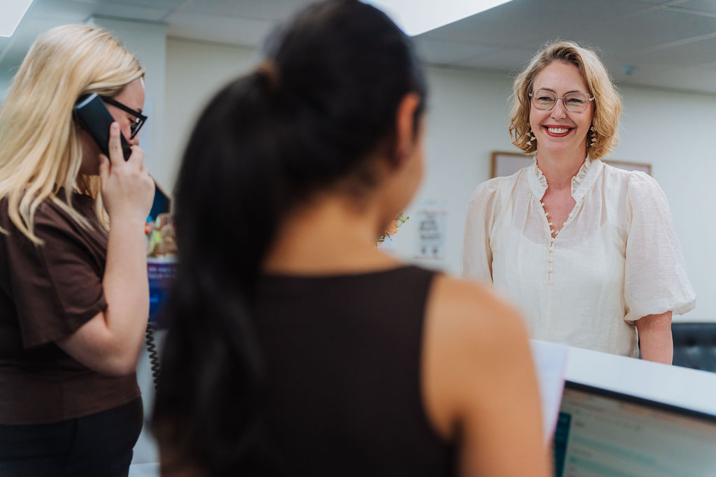 A Totally Psyched receptionist smiling as she greets a visitor at the front desk