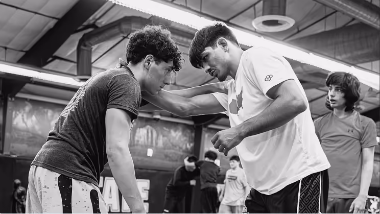 Wrestling coach providing individual instruction to an athlete during training