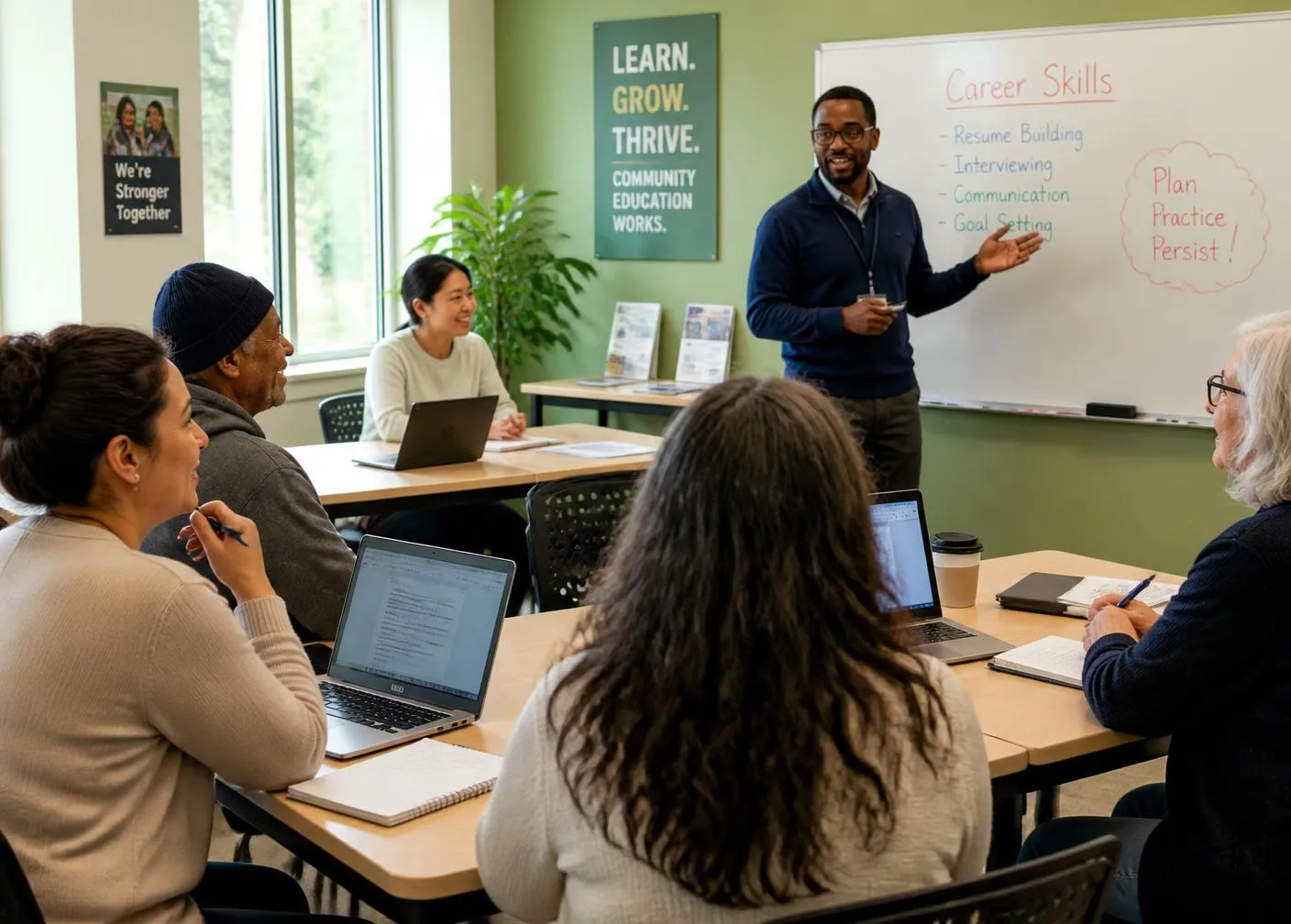 Instructor teaching diverse adult students career skills in a classroom with laptops and notebooks.