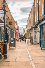 Narrow paved street lined with brick shopfronts and cafes