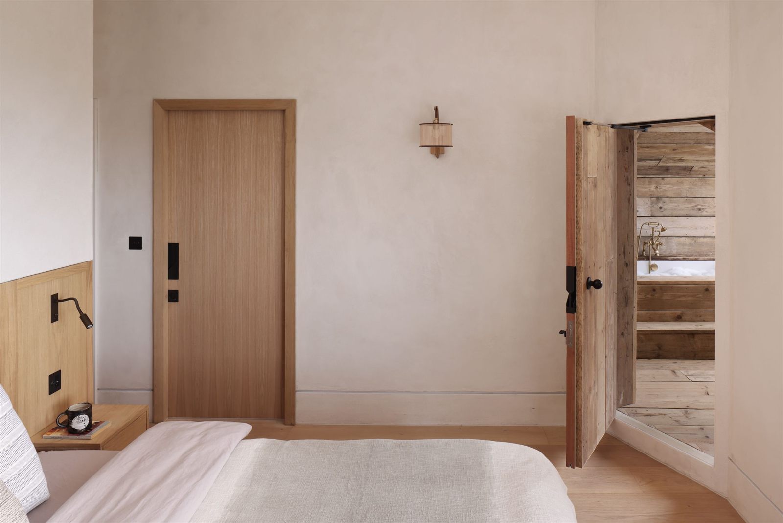 Bedroom with an oak door standing open onto the timber-lined bathroom