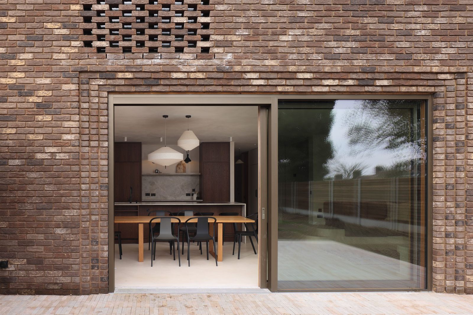 Sliding door open onto the kitchen, below a perforated brick panel