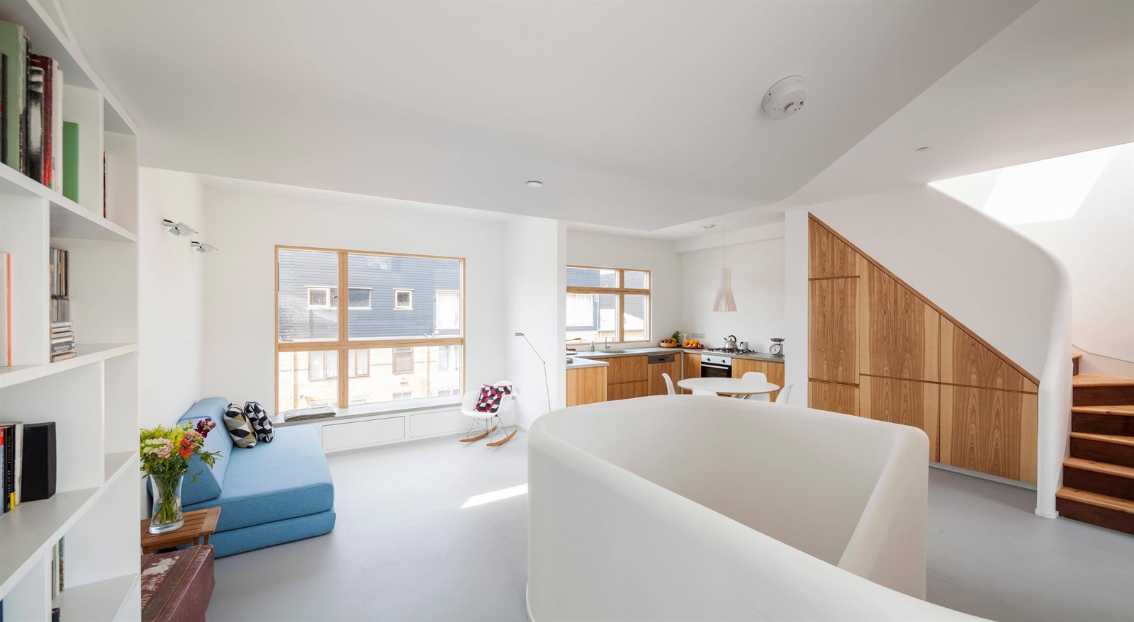 Living, dining and kitchen sharing one floor, with a curved stair enclosure at its centre
