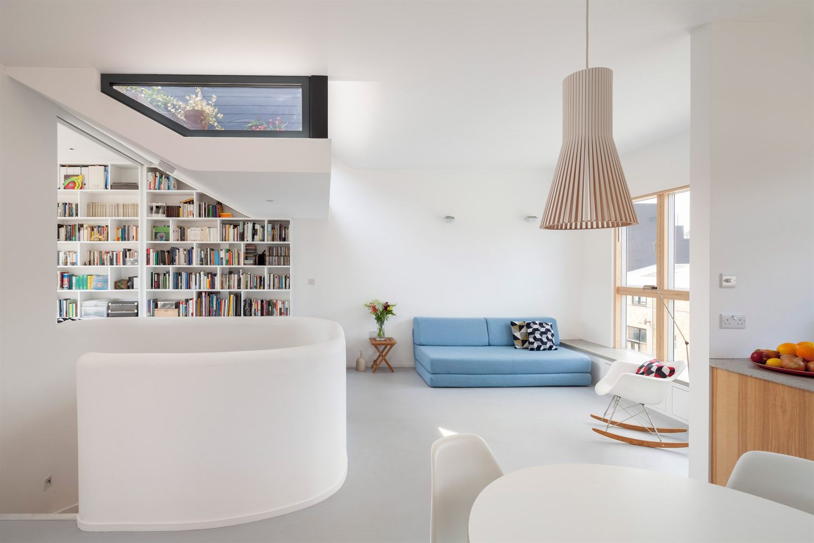 Open-plan living space with floor-to-ceiling bookshelves and a curved balustrade around the stair