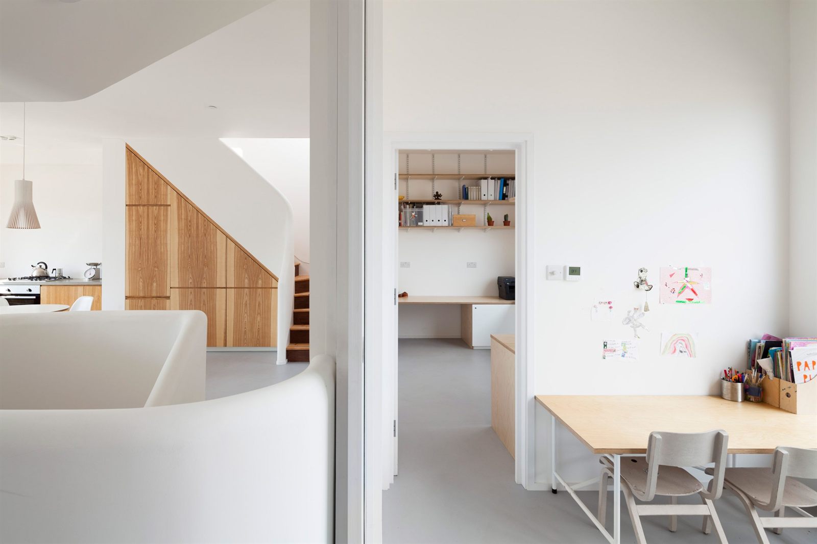 Oak understairs joinery beside a study, with a children's table and artwork on the wall