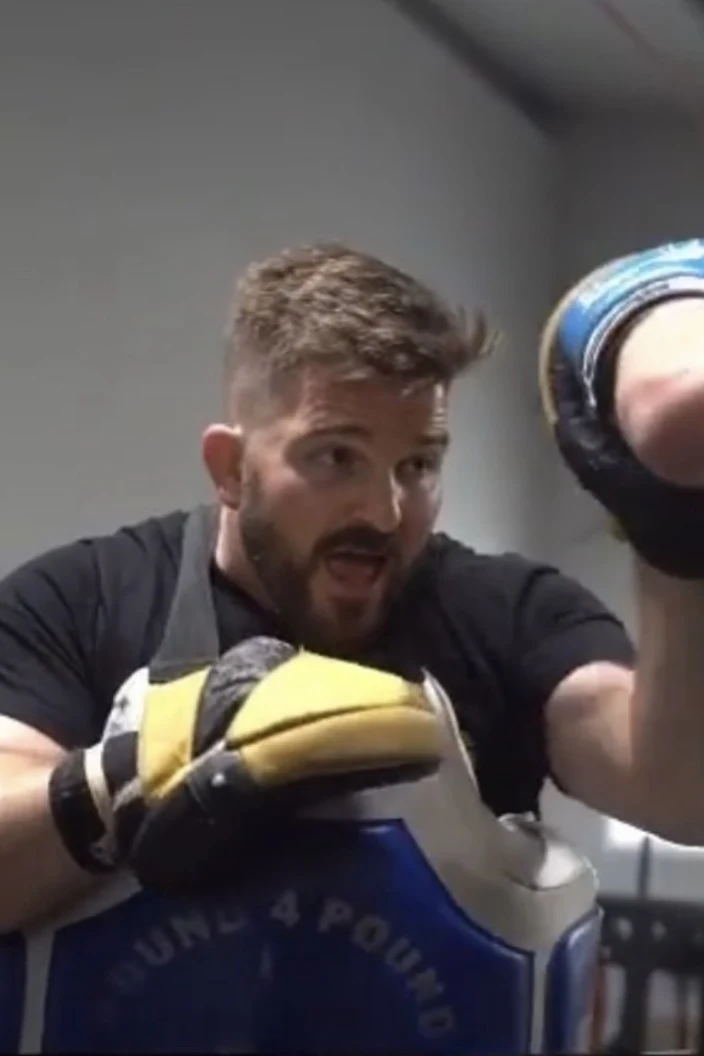 Coach holding focus mitts for a striking student at Rochester Combat Sports