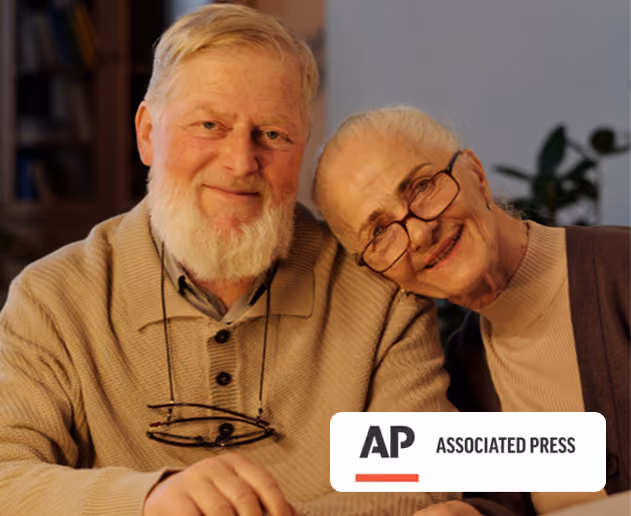 Article thumbnail showing a smiling elderly couple sitting close together indoors, woman leaning her head on man's shoulder with associated press logo.
