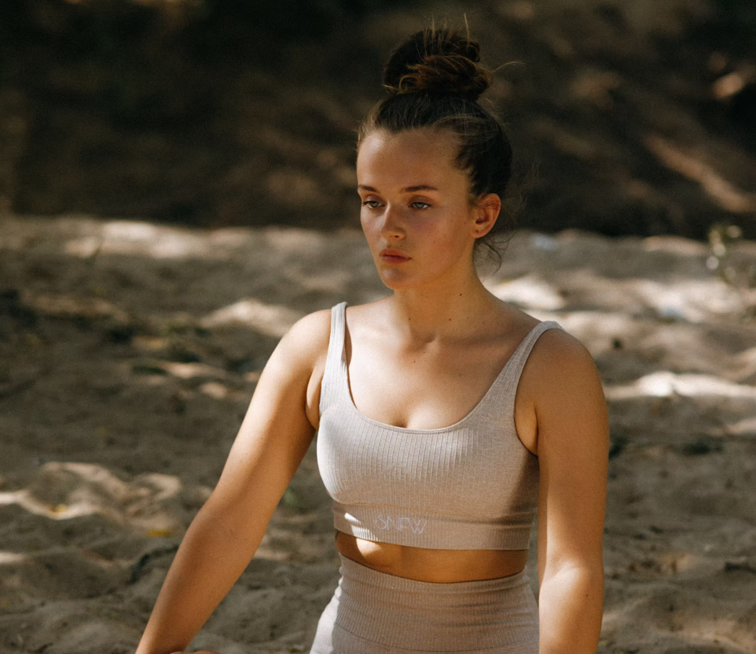 Young woman practicing guided meditation seated on grass outdoors