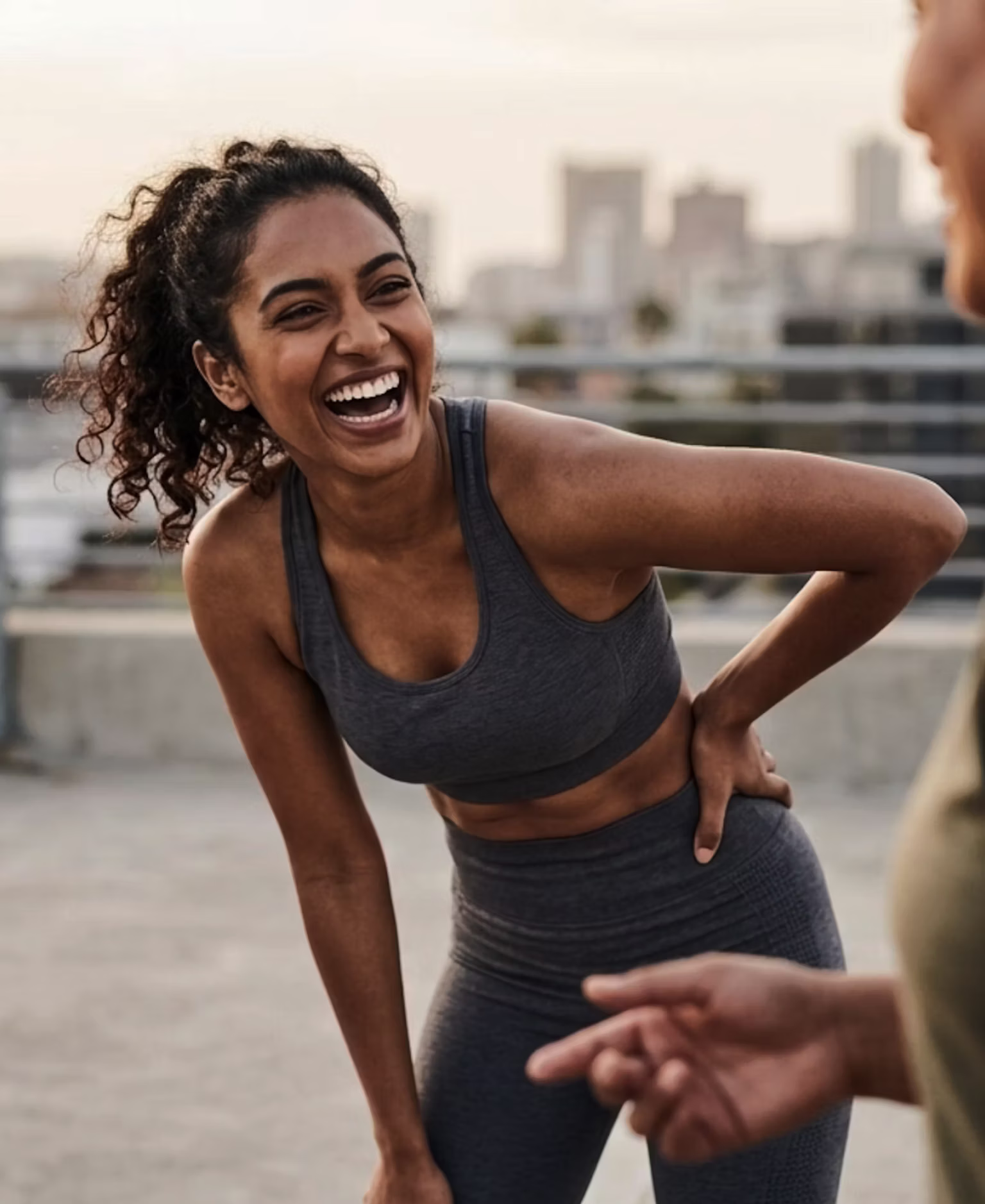 Two friends laughing together during a rooftop fitness session