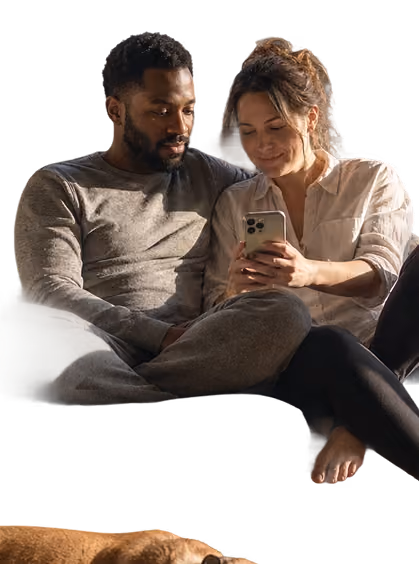 Couple sitting closely looking at a smartphone screen together, appearing engaged and relaxed.
