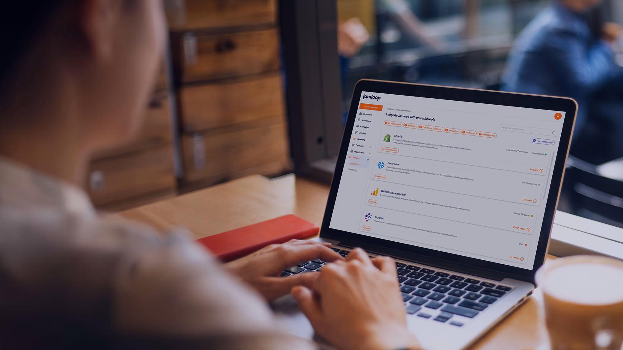 Person working on a laptop showing a software interface with a list of app integrations including Shopify, Snowflake, Metabase Analytics, and Twilio on the screen.