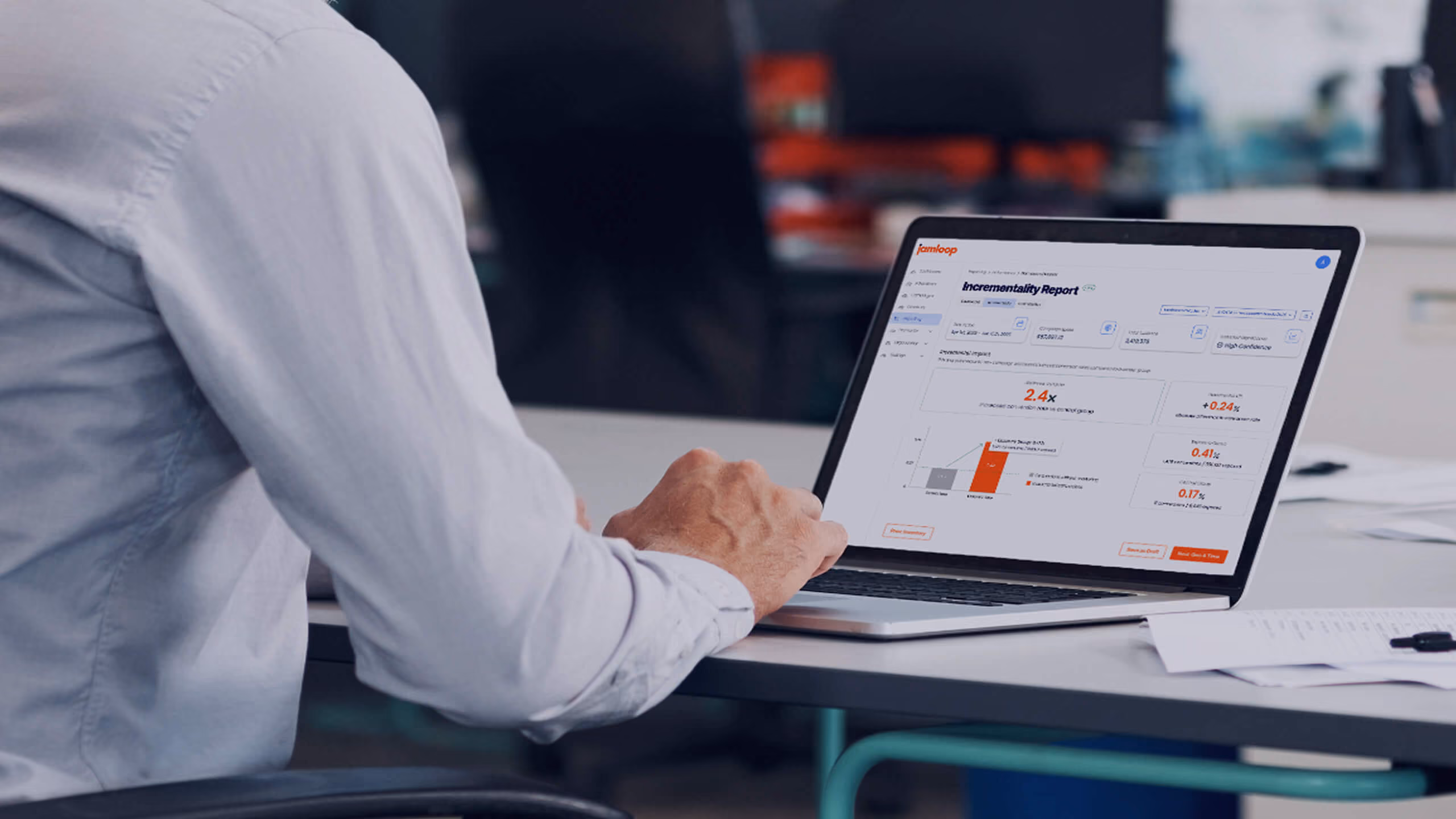 Person in a white shirt using a laptop on a desk displaying a software report with graphs and data metrics.