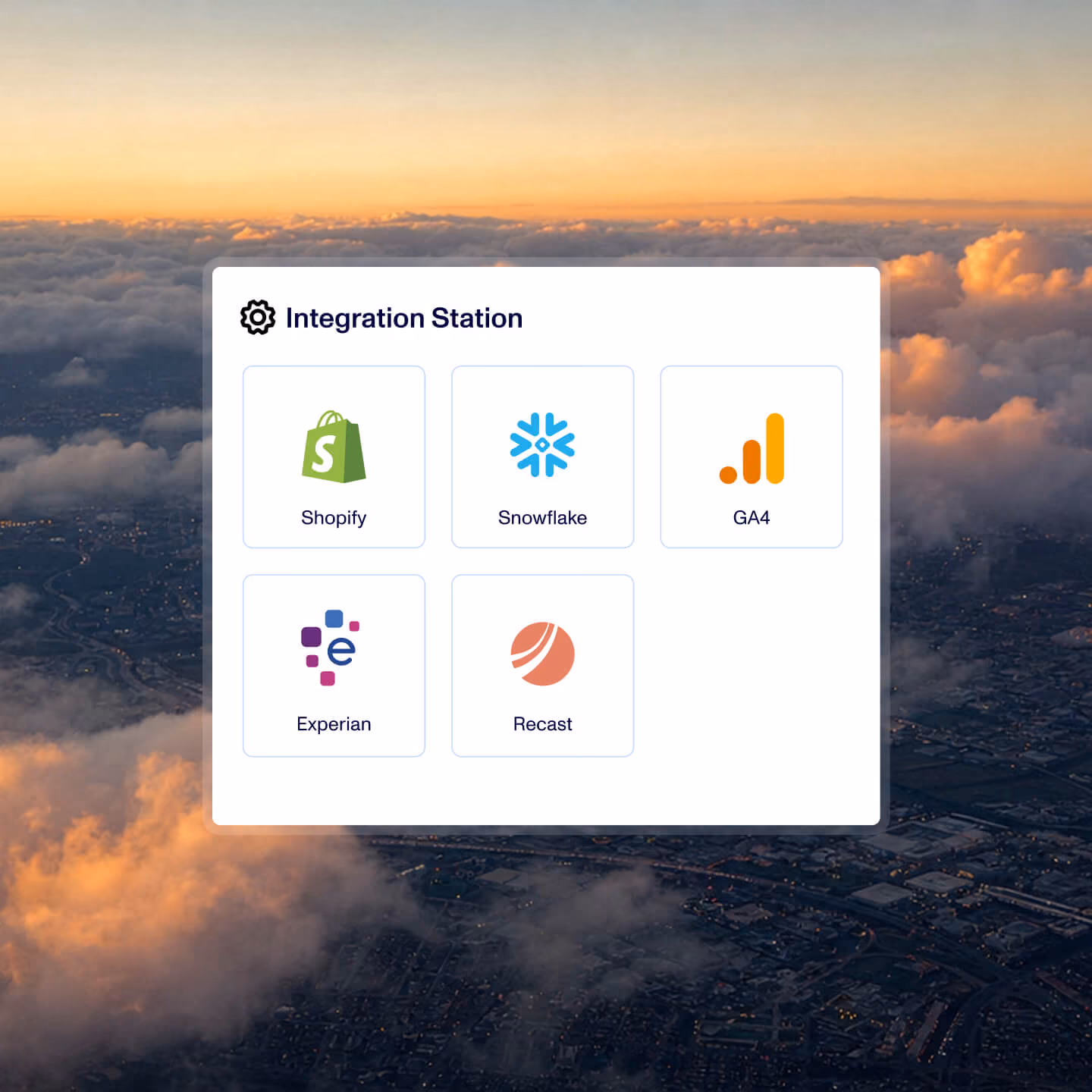 A white panel titled Integration Station containing icons and names of five software platforms: Shopify, Snowflake, GA4, Experian, and Recast, against a backdrop of a sunset sky with clouds over a city.