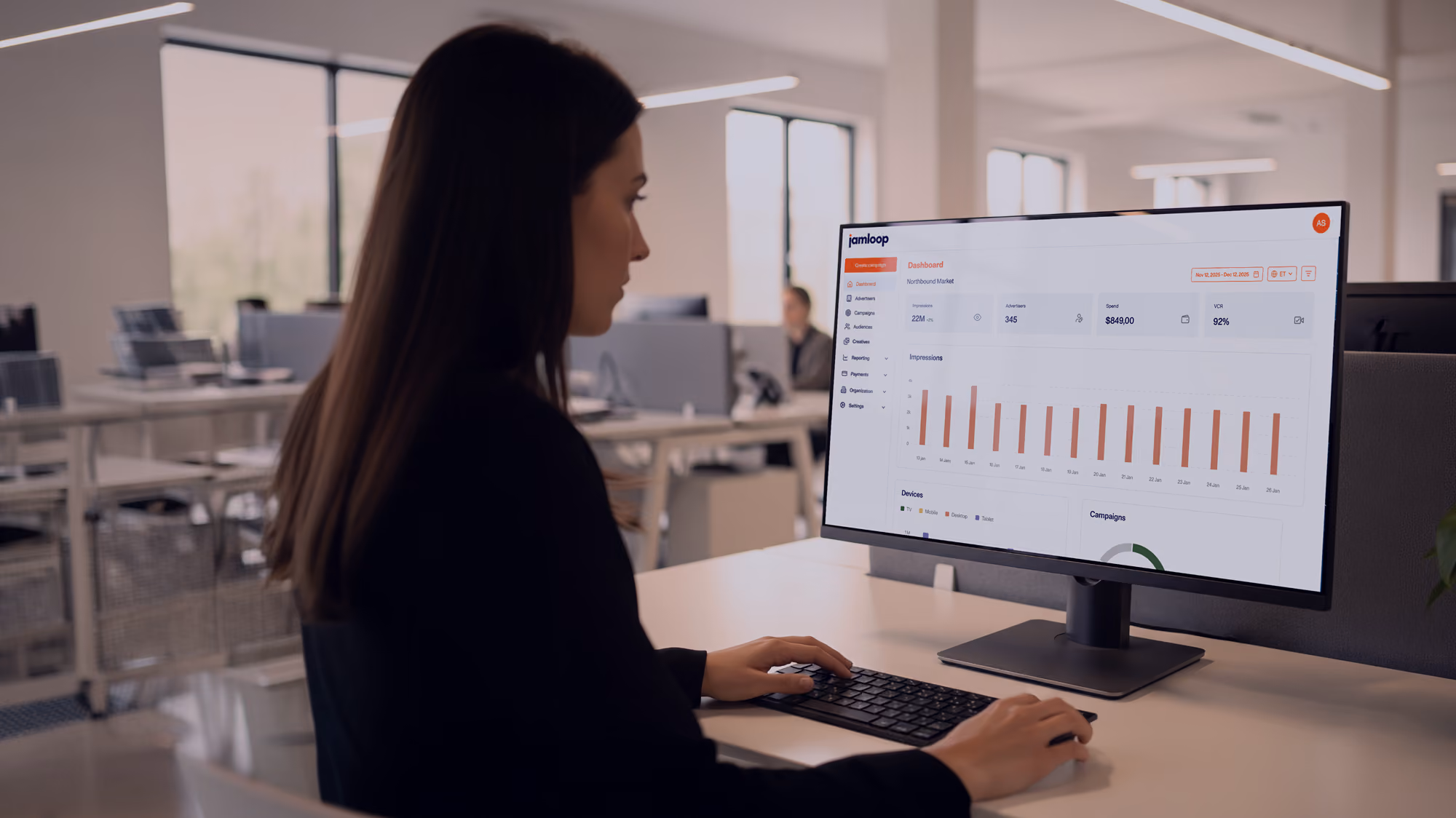 Woman in an office reviewing campaign performance on the JamLoop dashboard