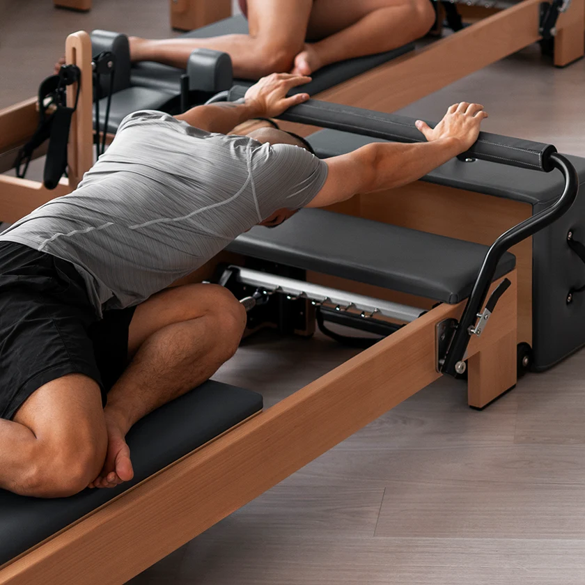 Homme en train de s'étirer sur Pilates reformer