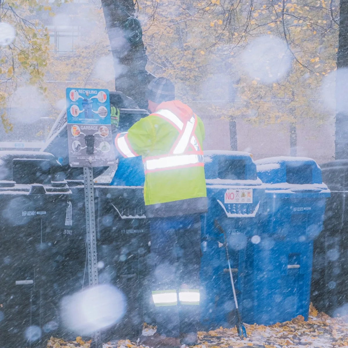 Miljöarbetare vid soptunnor i regnet