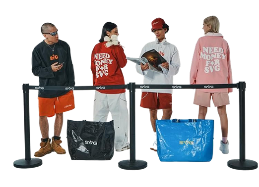 Four people in branded streetwear waiting behind a queue barrier