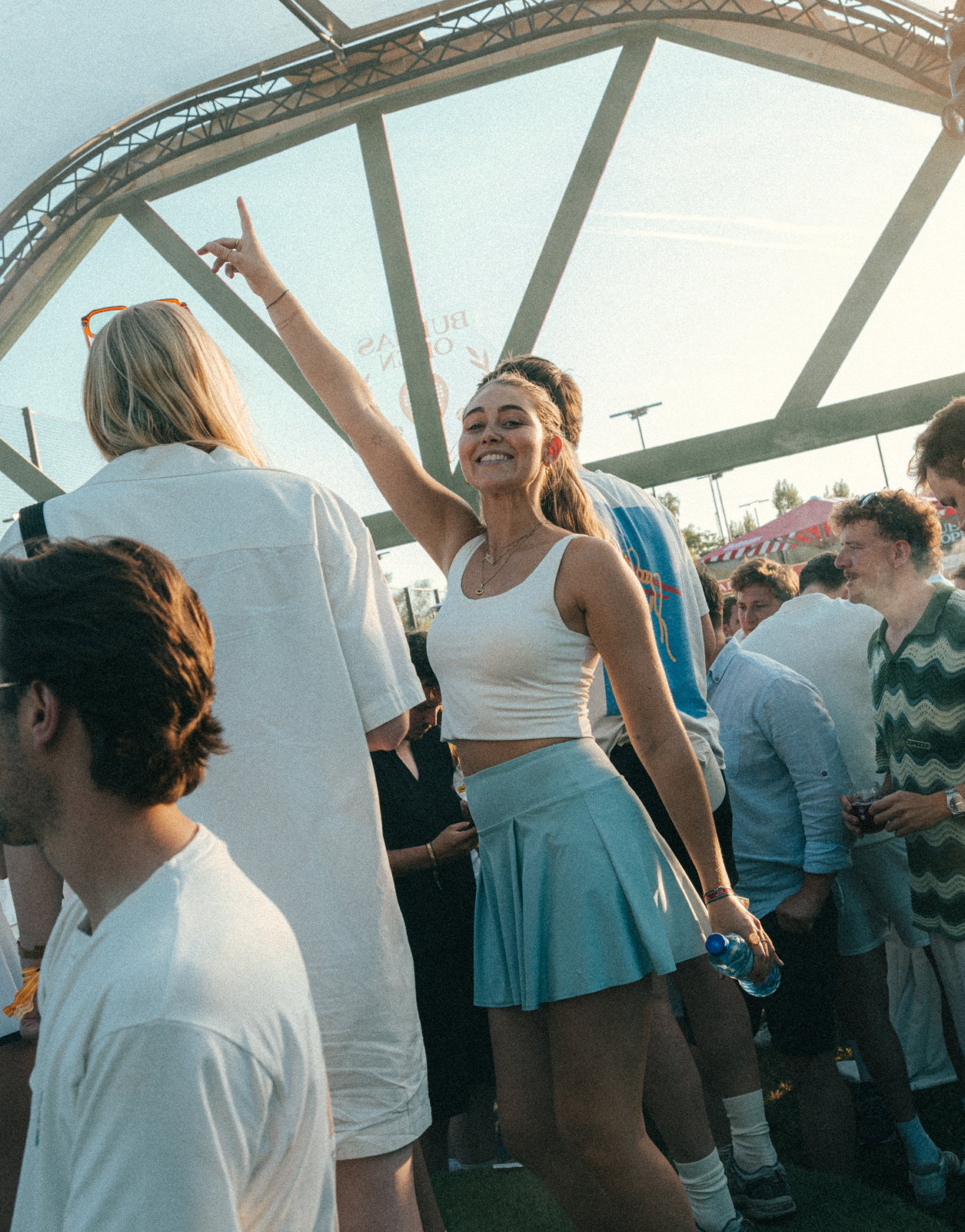 Crowd at an outdoor summer event, one person dancing with her arm raised