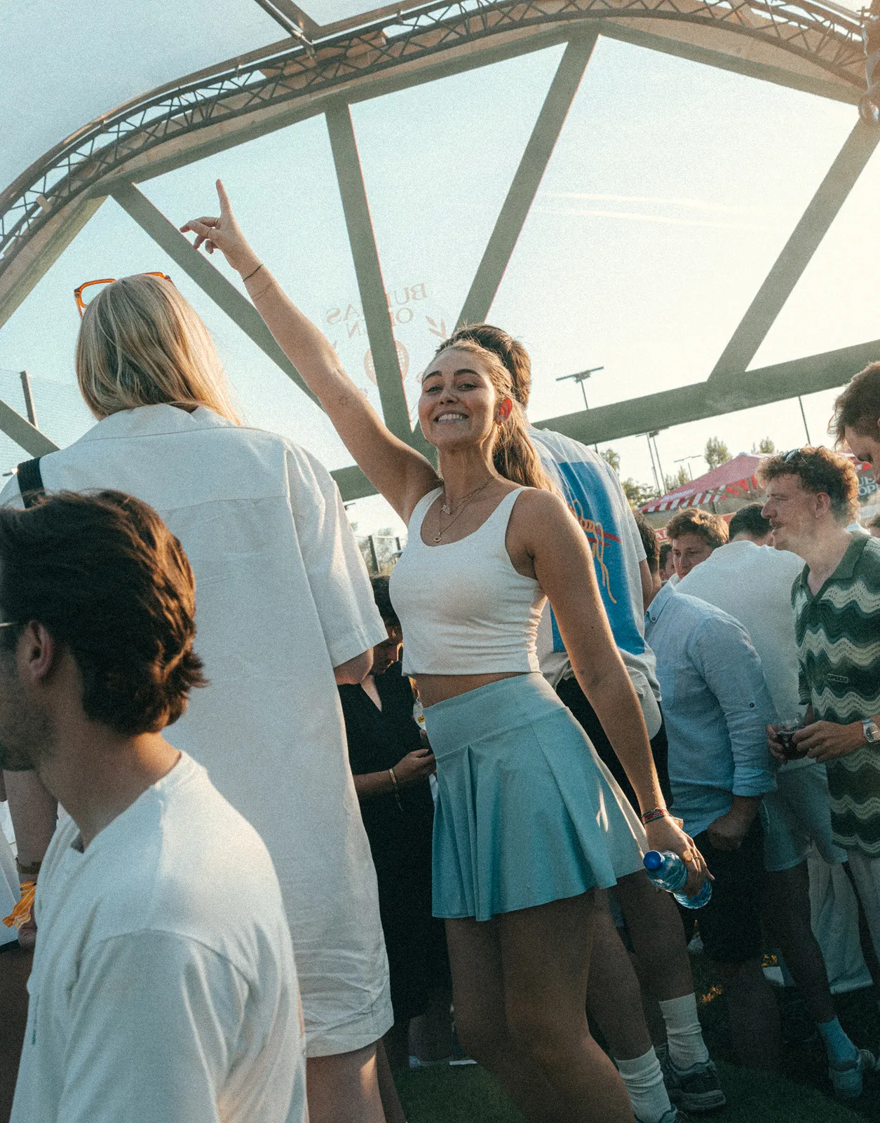 Crowd at an outdoor summer event, one person dancing with her arm raised