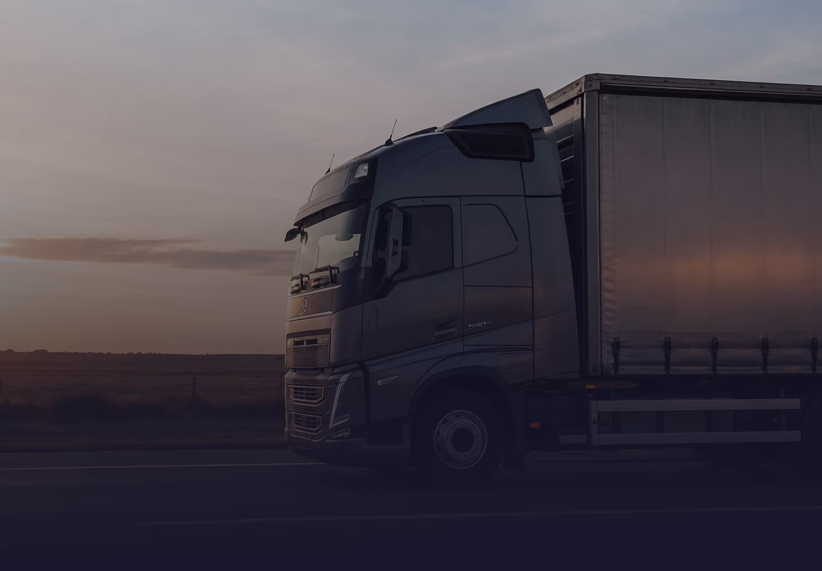 Camión Volvo circulando por la ruta durante el atardecer.