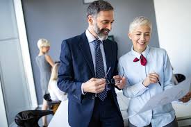Two business professionals smiling and reviewing documents together in a modern office.