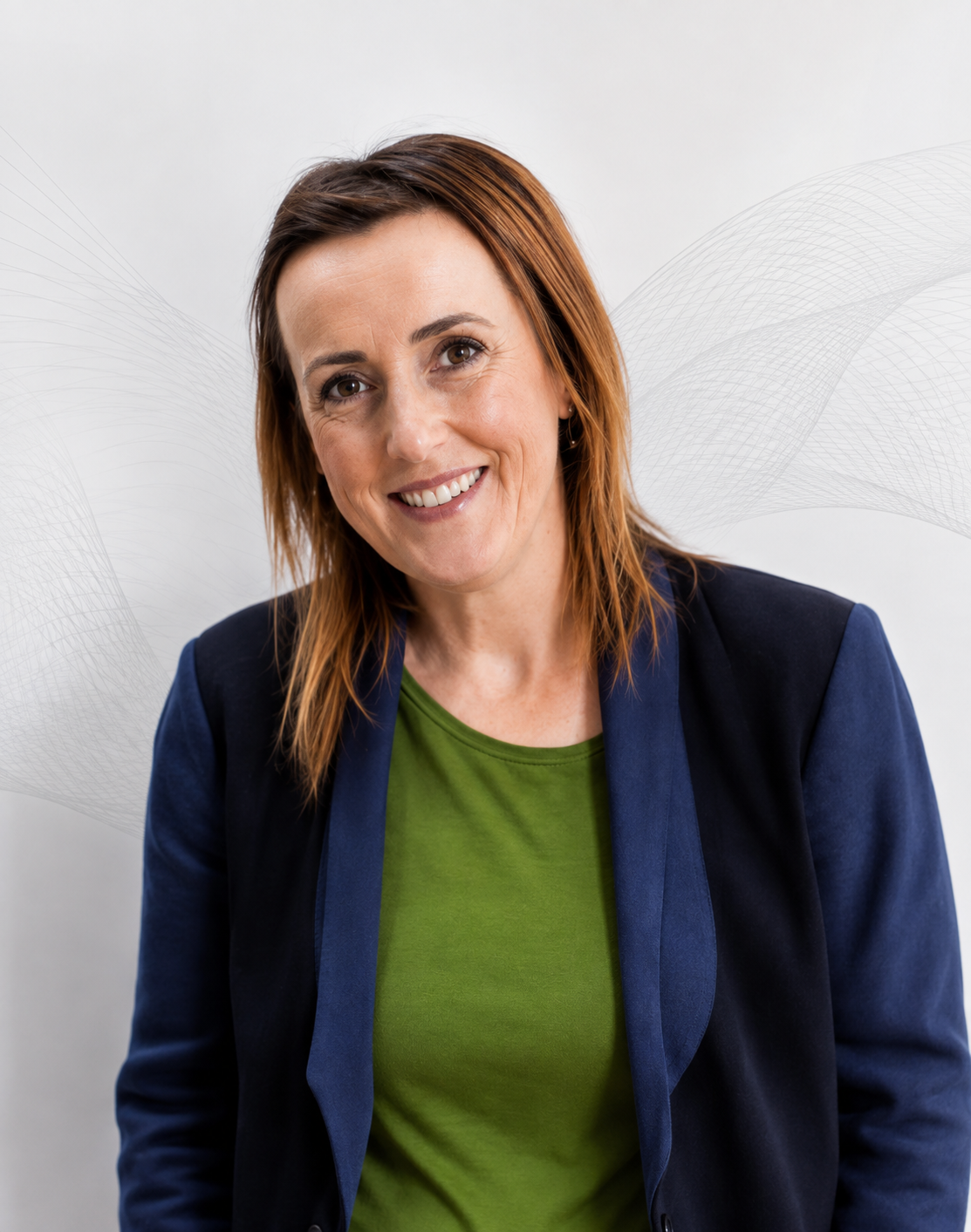 Professional headshot of woman with reddish-brown hair wearing navy blazer and green shirt.