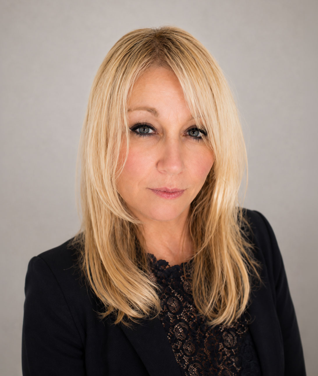 Professional headshot of a woman with blonde hair wearing black lace top
