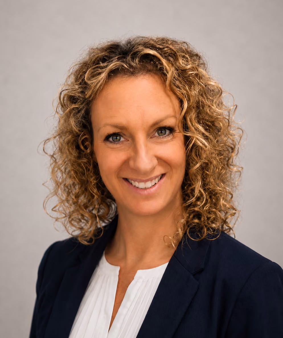 Professional headshot of woman with curly brown hair smiling at camera
