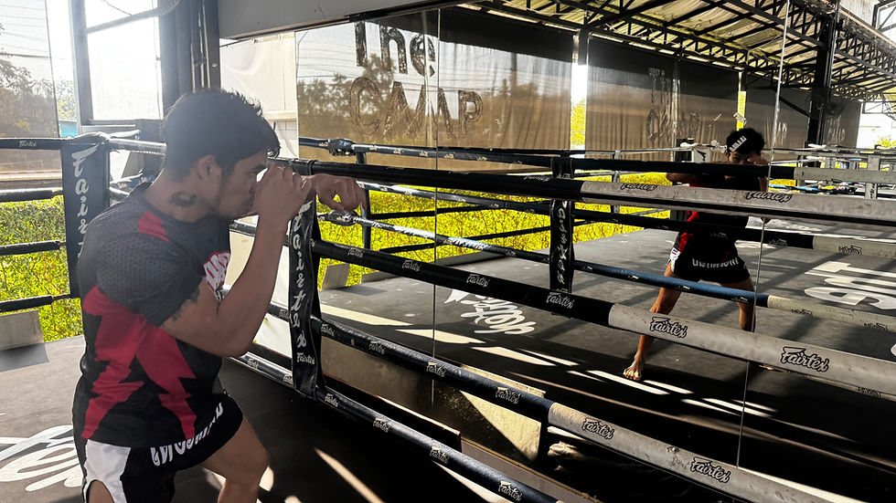 Muay Thai trainee shadowboxing in front of a mirror inside a ring at The Camp Chiang Mai