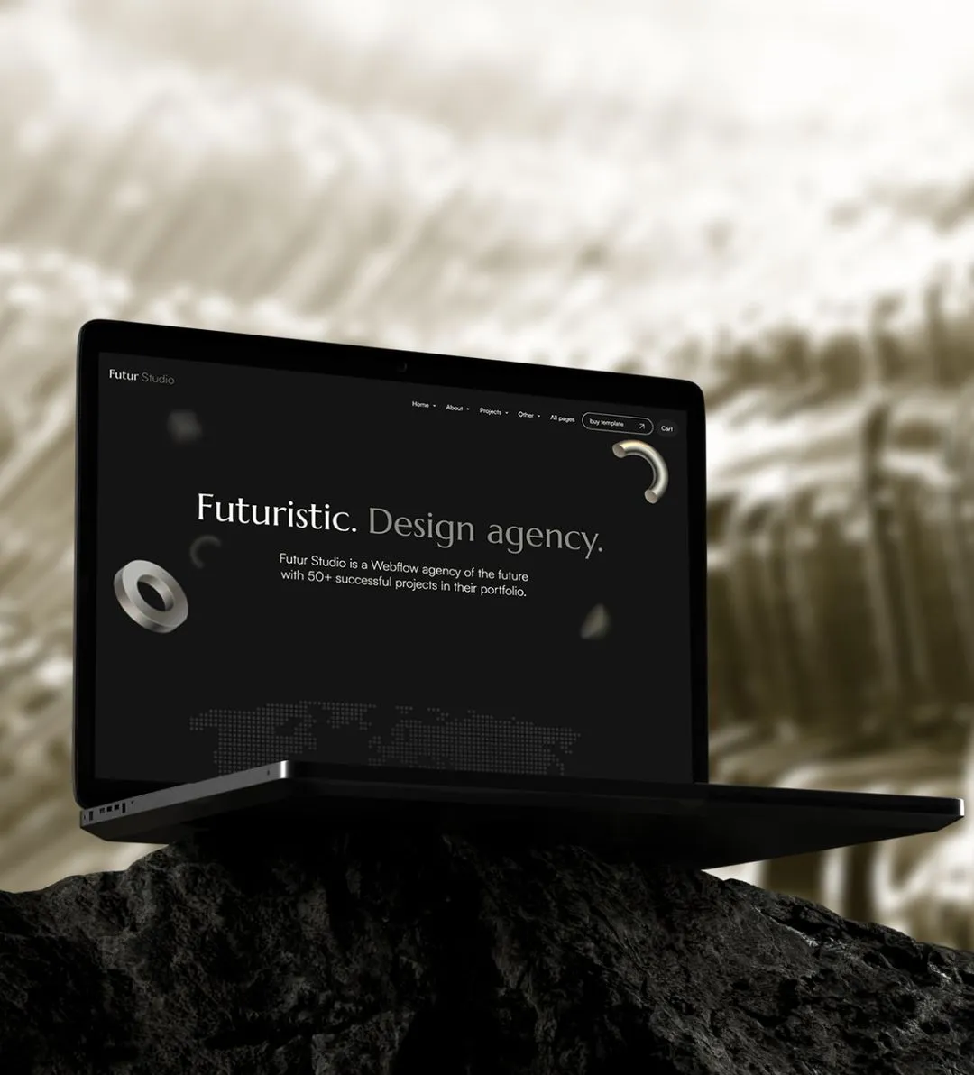 Open laptop displaying a dark-themed website homepage of Futur Studio, a futuristic design agency, placed on a black rock with a blurred background.
