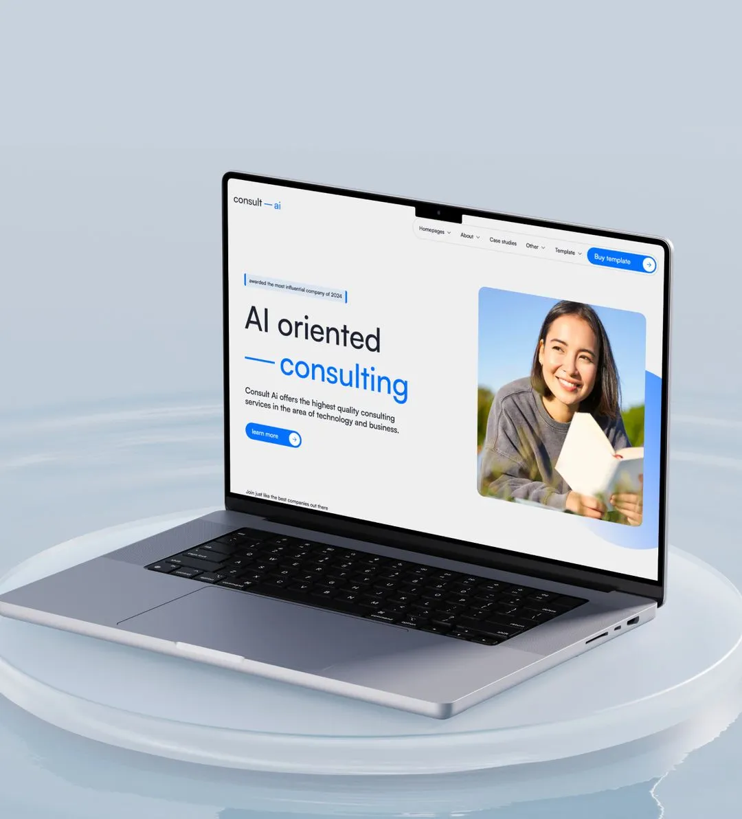 Silver laptop on a round pedestal displaying a consulting website with a smiling woman holding a book.