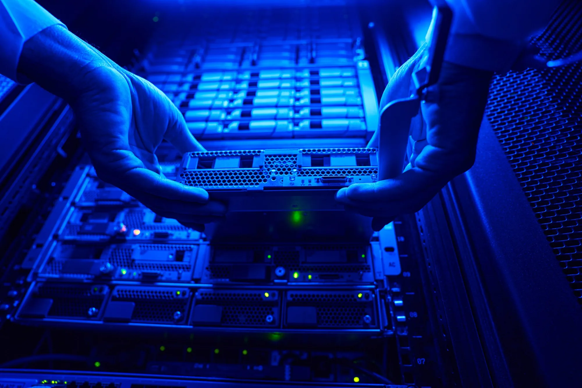 Hands installing network hardware in a data center rack