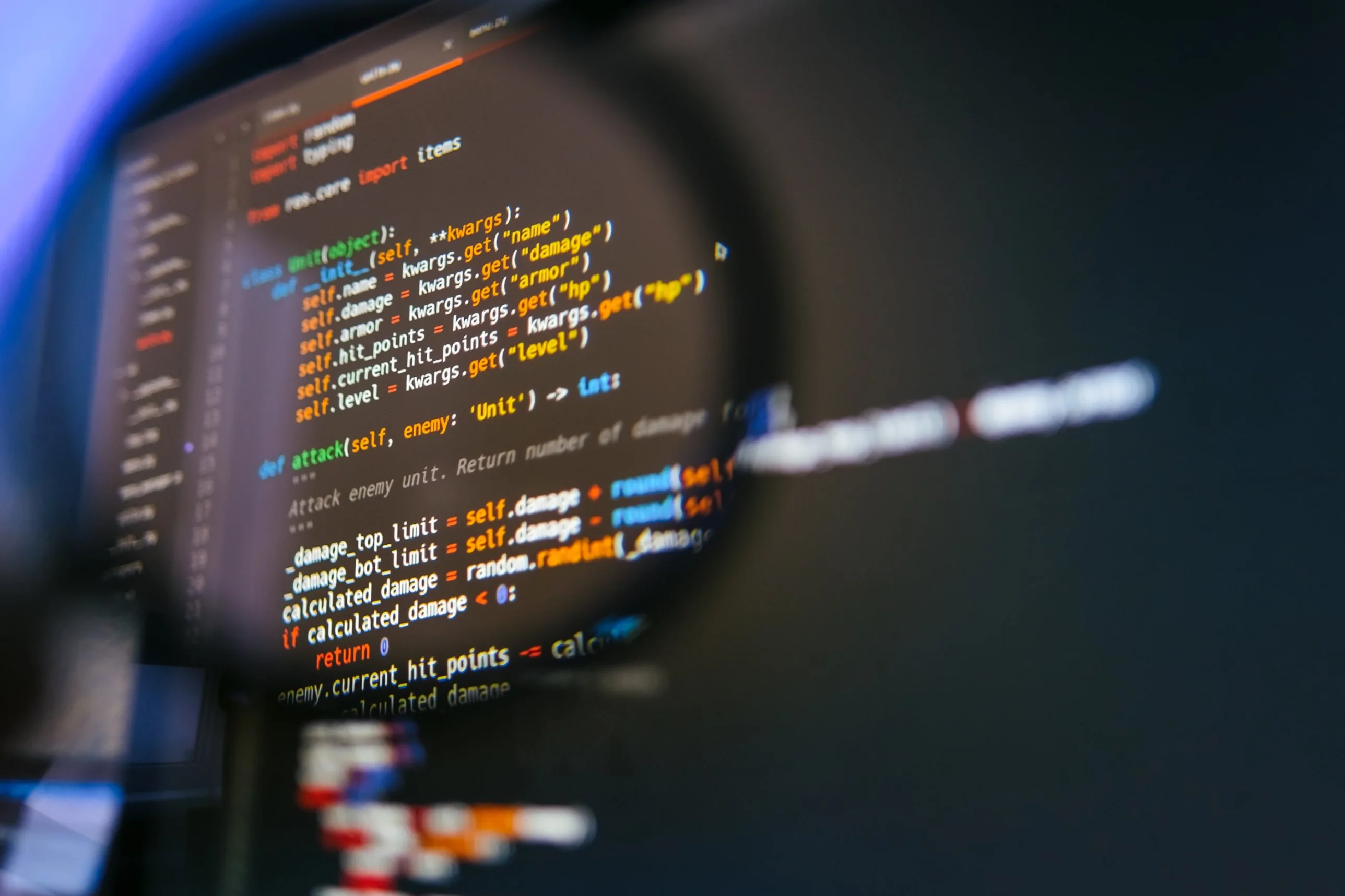 Source code on a monitor viewed through a magnifying glass