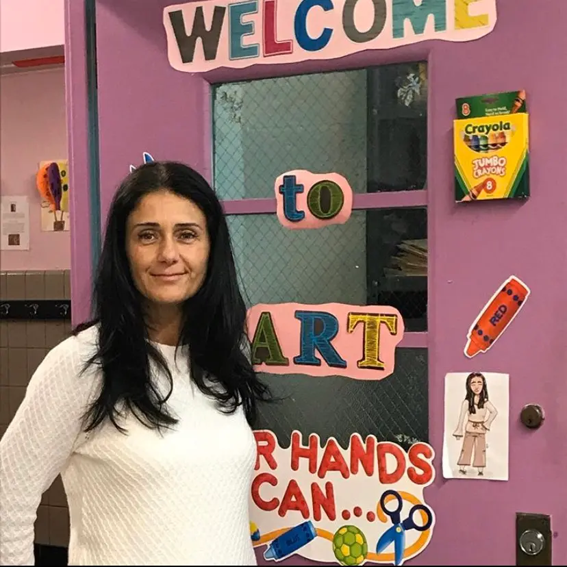 Art teacher standing in front of decorated Welcome to Art classroom door