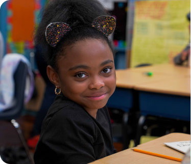 Smiling elementary student sitting at her classroom desk