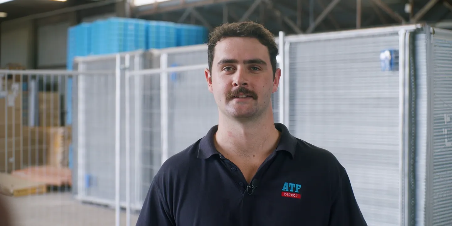 Man with mustache wearing a navy blue ATF Direct polo shirt inside a warehouse.