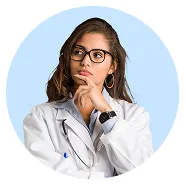 Thoughtful female doctor with glasses in a white coat and stethoscope against a blue background.
