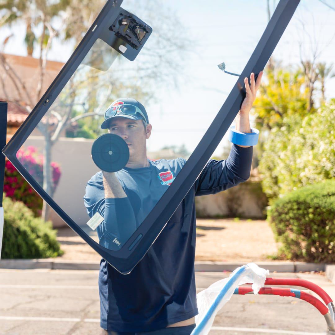 Technician handling a replacement windshield before installation in Phoenix