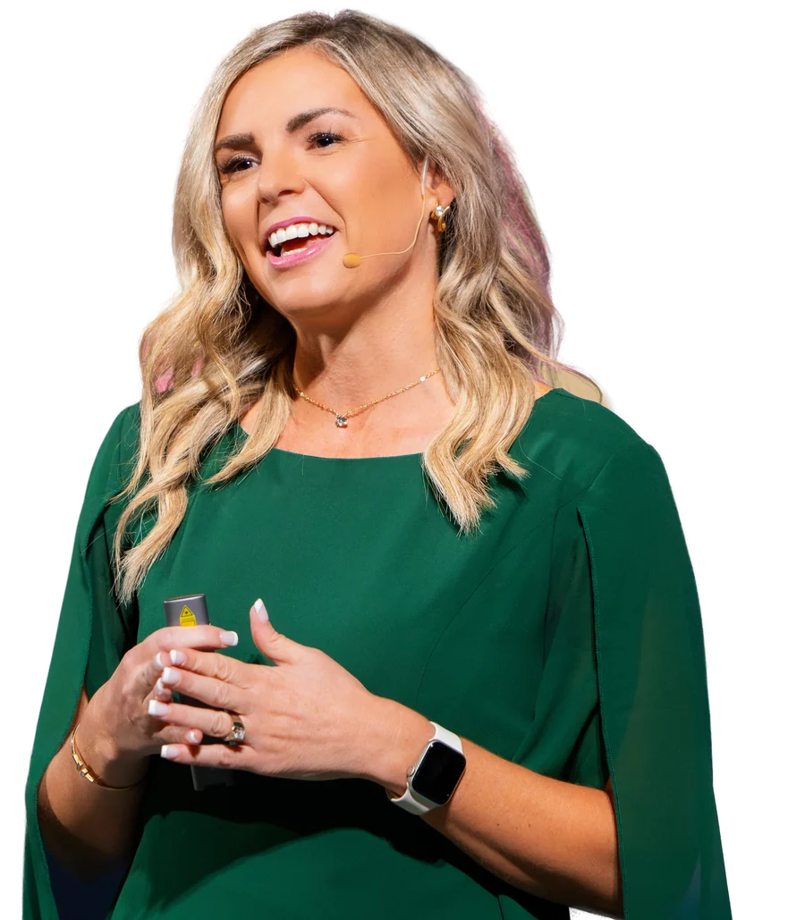 Missy Moss Wright laughing on stage with her hand over her heart, wearing a headset microphone