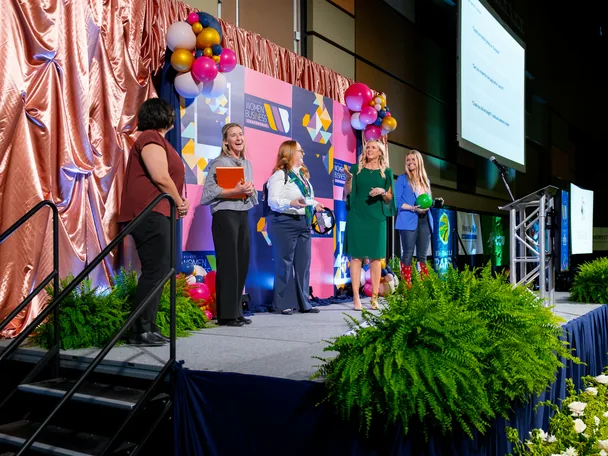 Missy Moss Wright on stage with a group of women at a conference