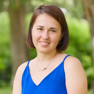 Retrato de Veronika. Una mujer sonriente con vestido azul y fondo natural difuminado.