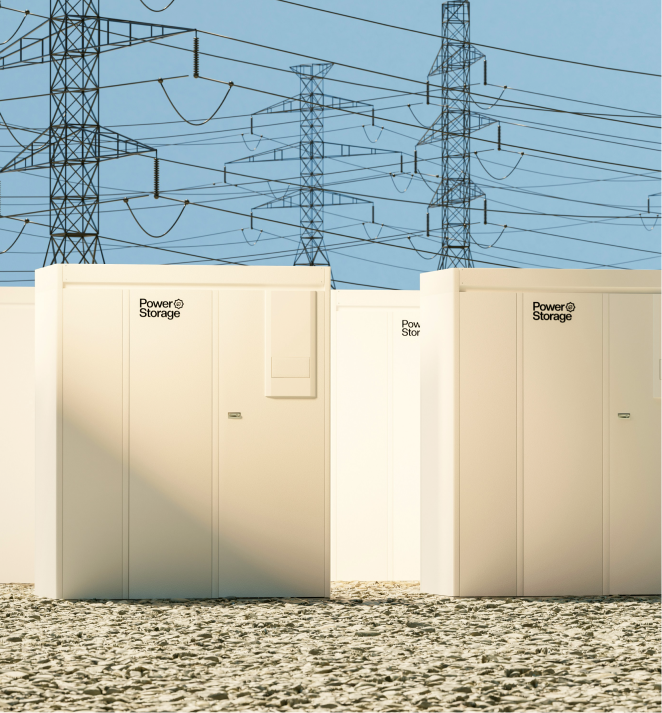 White power storage units on gravel under blue sky with multiple electrical transmission towers in the background.