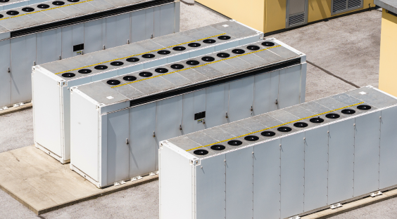 Four large industrial cooling units with multiple circular fans on top, installed outside a building.