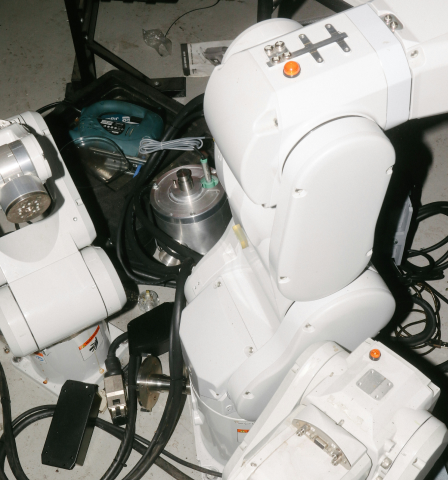 Close-up view of white robotic arms with cables and mechanical parts on a workshop floor.
