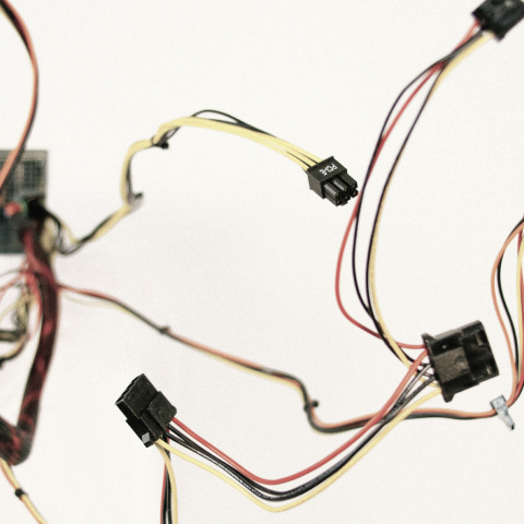 Close-up of various computer power supply cables and connectors with colored wires against white background.