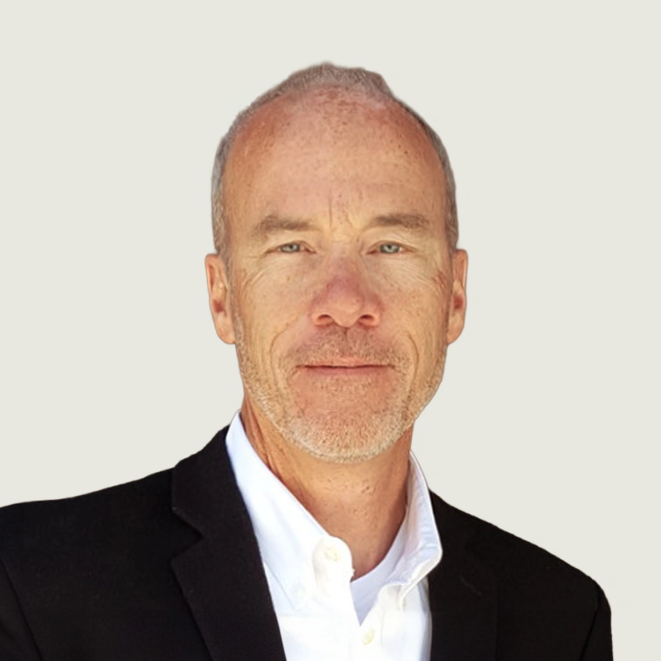 Middle-aged man with a light beard wearing a black blazer and white shirt against a plain background.