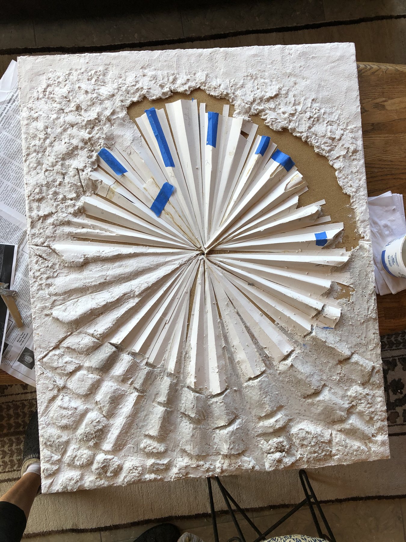 A work in progress on a studio table, blue tape marking out a radiating pattern